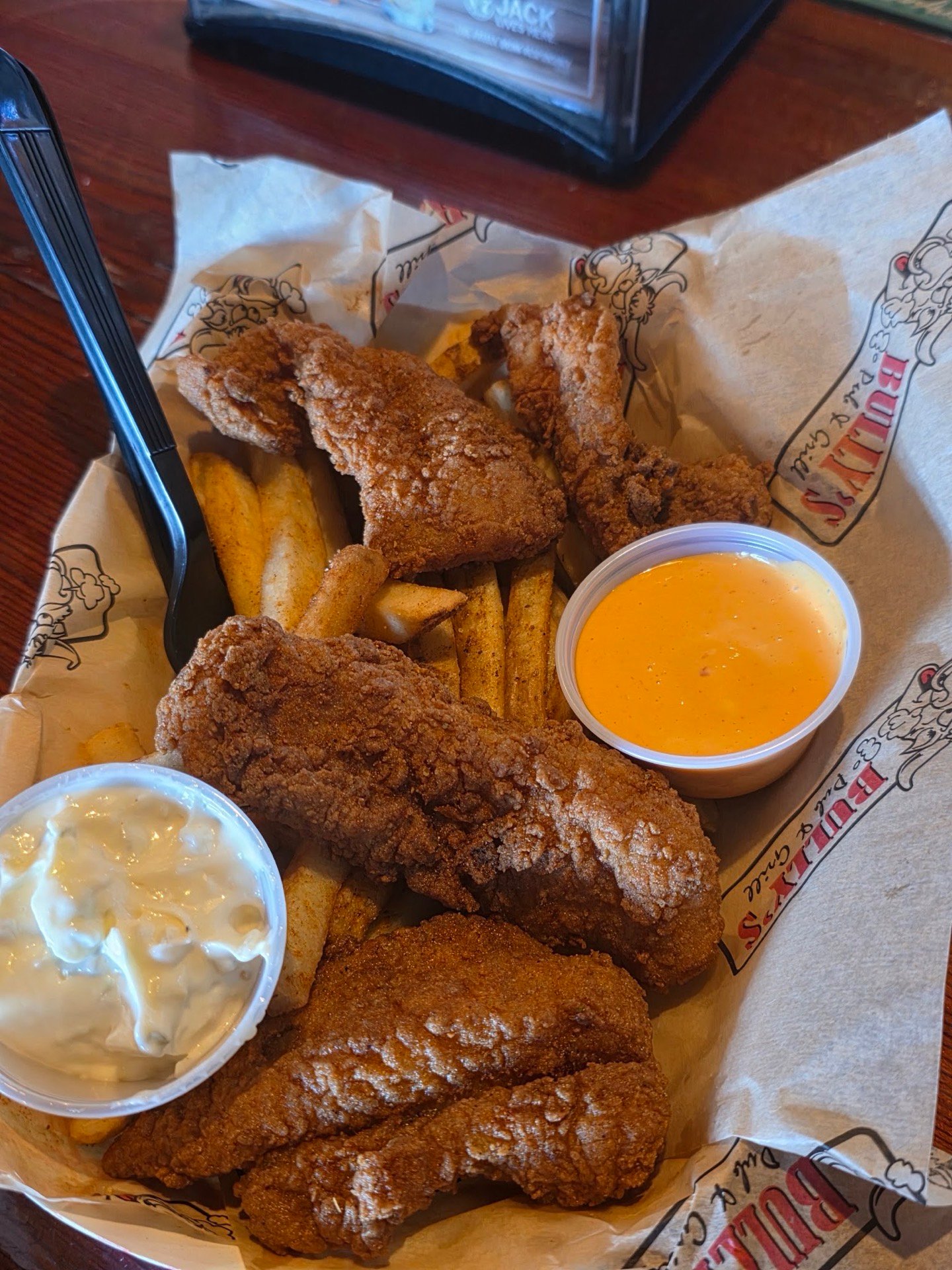 Chicken fingers and fries with a cup of cheese sauce